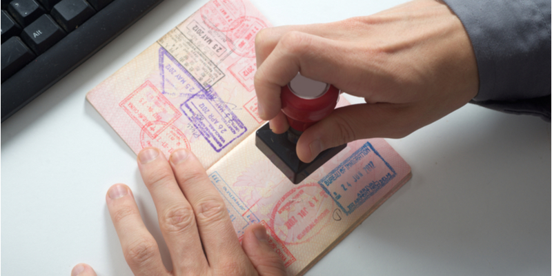 hand of an immigration officer about to stamp a passport using a date stamp