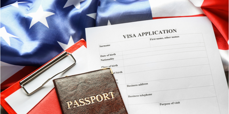 Passport, writing pad, visa application form and the American flag on table. Immigration to USA