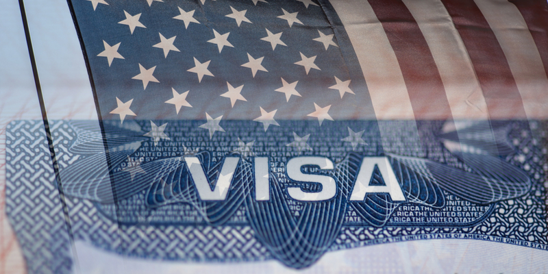 US visa document with the flag of the United States of America in the blurry background.