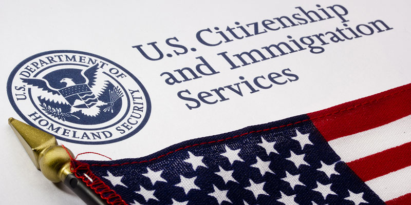 Close-up of the US Citizenship and Immigration Services logo with the small American flag nearby