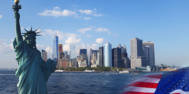 The statue of liberty with landmarks of New York City background and waving US flag in the corner