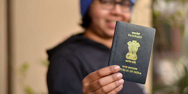Portrait shot of a young woman wearing a blue cap and holding her passport