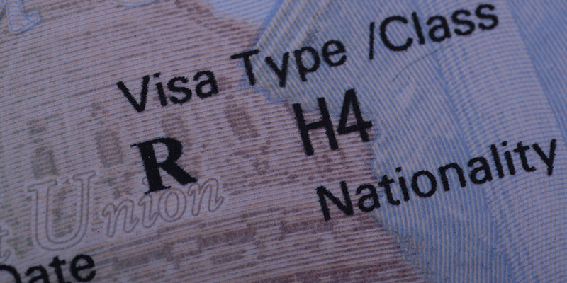 A macro shot of the stamped USA H4 visa in a passport.