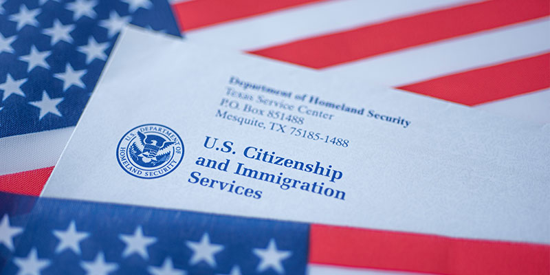 Covered in the flag of the United States is a document with the U.S Citizenship and Immigration Services logo and the Department of Homeland Security address