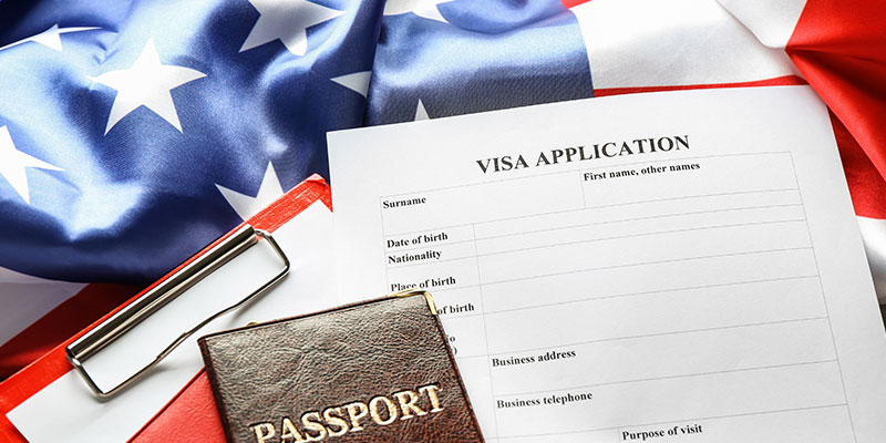 Passports, a notepad, a visa application form, and the American flag on the table