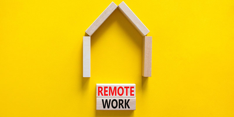 On a yellow background, wooden blocks with the words Remote Work appear near a miniature wooden house