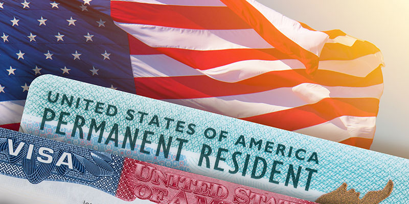 Image of the American flag waving at the back of the picture of green card and US Visa in passport.