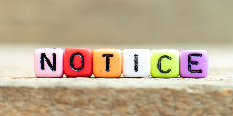 Image of colorful cubes forming the word NOTICE on a wooden background