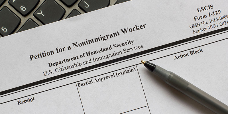Image of Form I-29, a petition to non-migrant workers kept on a computer keyboard, with a pen on top.